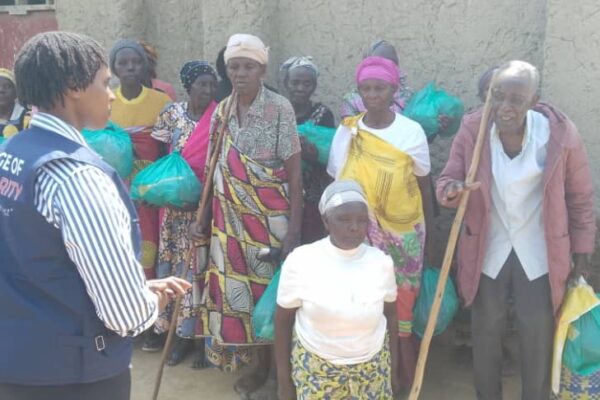A Bridge of Solidarity agent in front of a group of vulnerable people after a clothing and shoe distribution session at the Nakivale camp, January 2025 (SOS Médias Burundi)